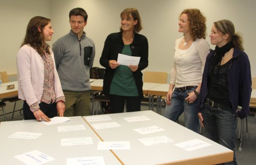 Foto: Menschen stehen um einen Tisch und diskutieren Kärtchen